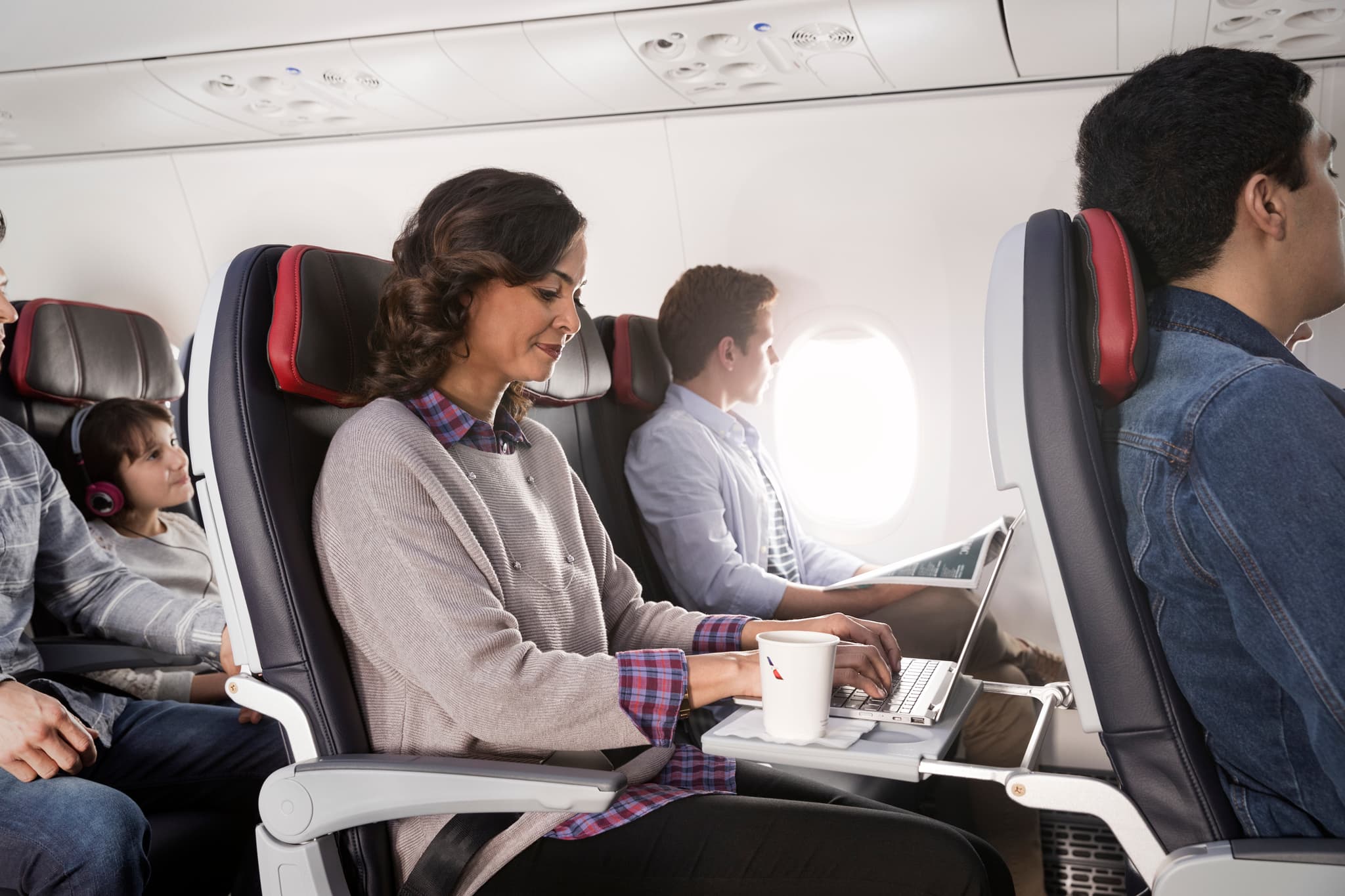 Woman seated on an airplane typing on a laptop